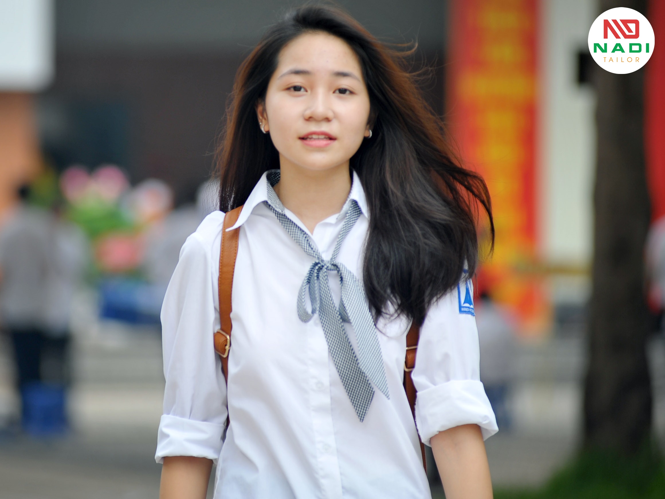 Đồng phục áo sơ mi dài tay cho nữ, kết hợp với nơ cổ và thiết kế logo của trường phía tay trái Đồng phục học sinh dành cho nữ